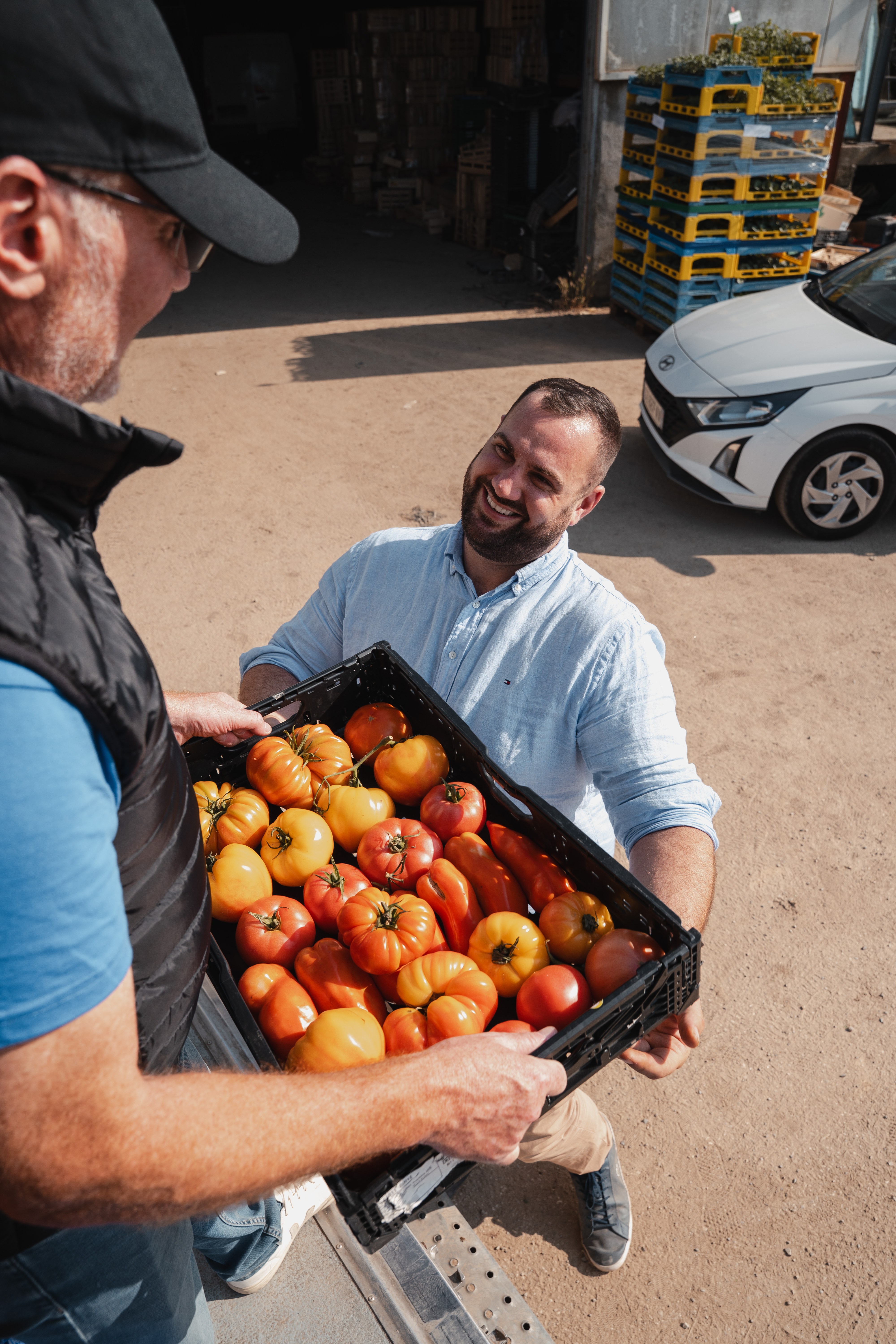 Deux personnes souriantes échangeant un caisson de légumes